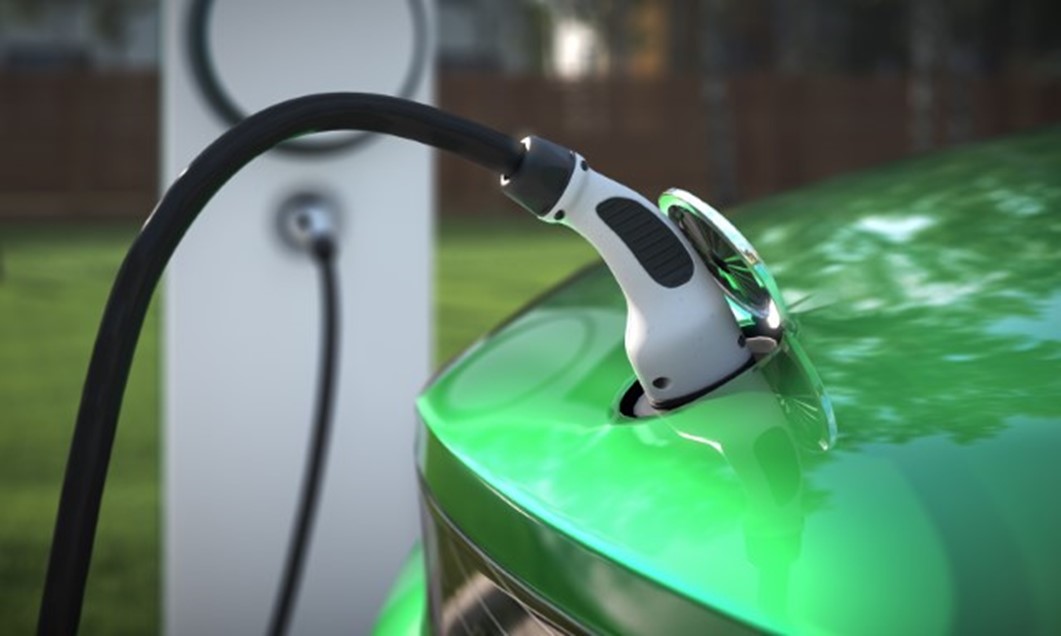 Green car plugged into electric charger