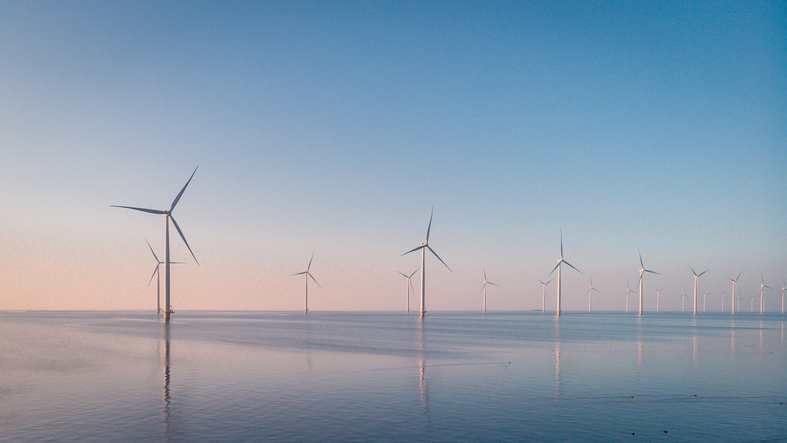 Wind farm over water at sunrise