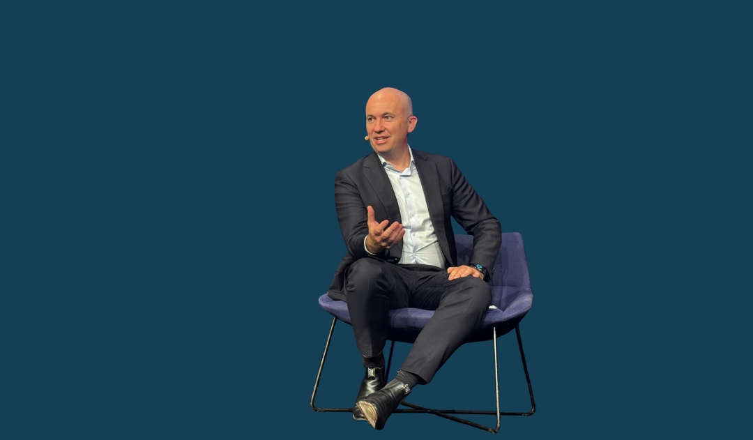 Matt Kean sitting on a chair with a solid dark blue background
