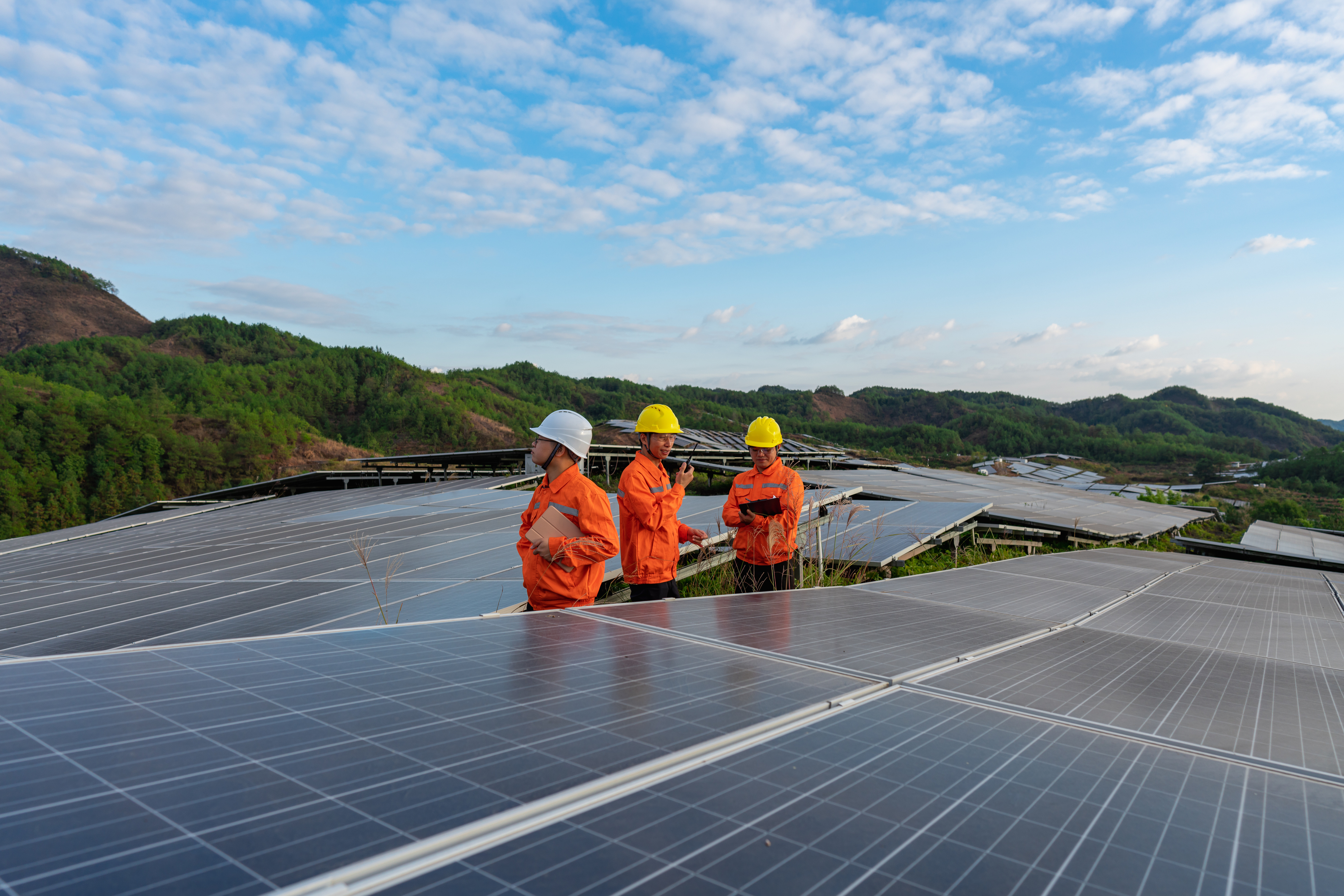 3 workers surrounded by solar panels