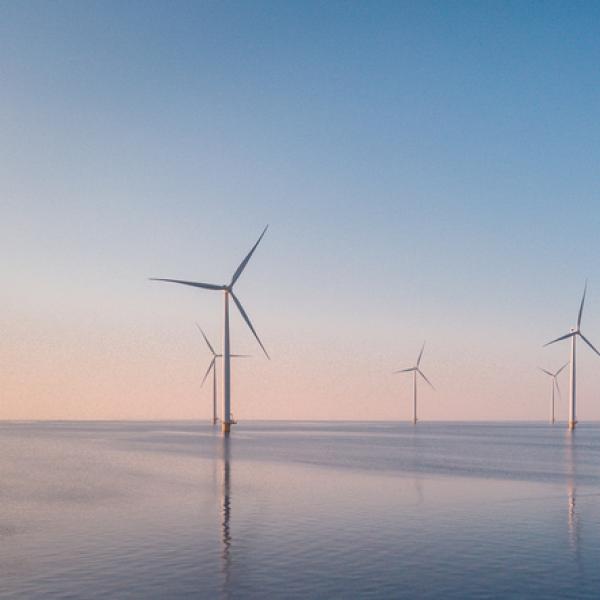 Wind farm over water at sunrise