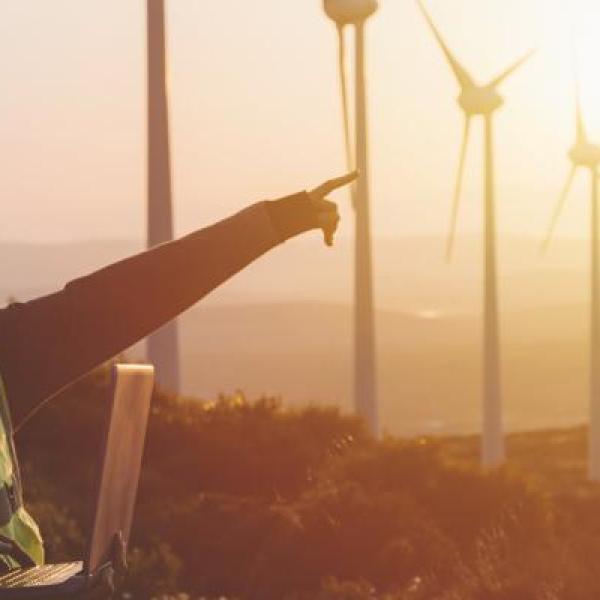 People in high vis work gear at sunset near wind turbines