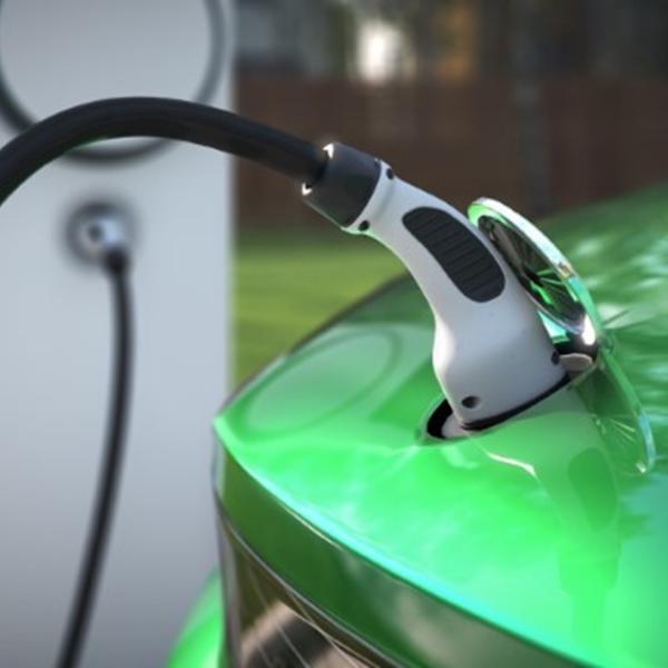 Green car plugged into electric charger