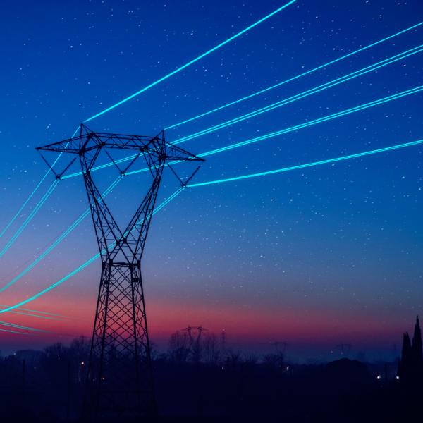 Electricity pilon with glowing cables over sunset sky