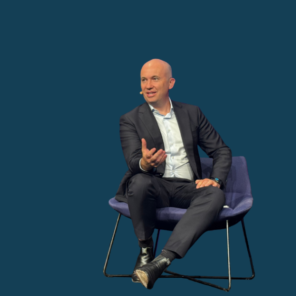 Matt Kean sitting on a chair with a solid dark blue background