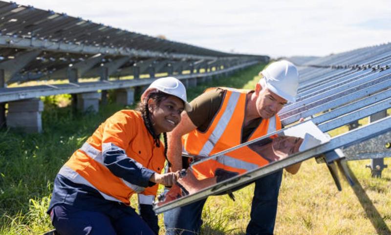 Senior Engineer and Aboriginal Australian Apprentice Working Together On Solar Farm Installation