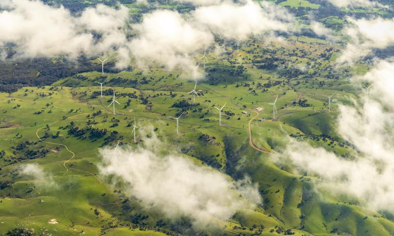 Aerial photograph; A group of wind turbines in an agricultural field from above the clouds
